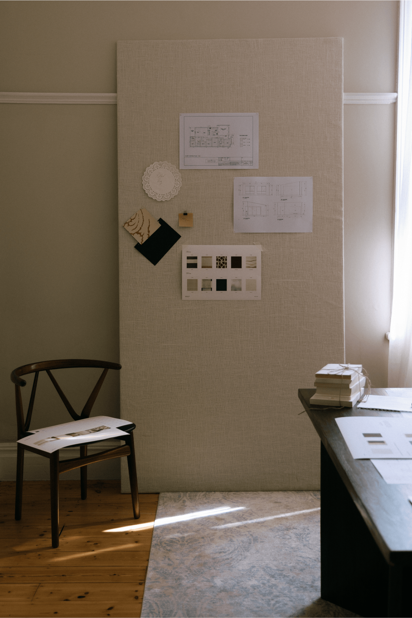 Room interior with a chair, desk, and wall with pinned papers and samples.